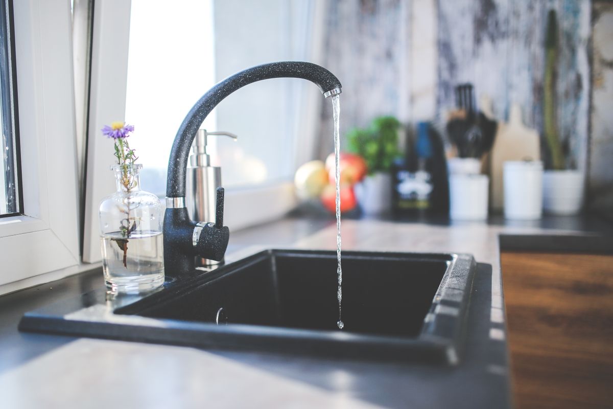 Water running from a kitchen tap into a stainless steel sink